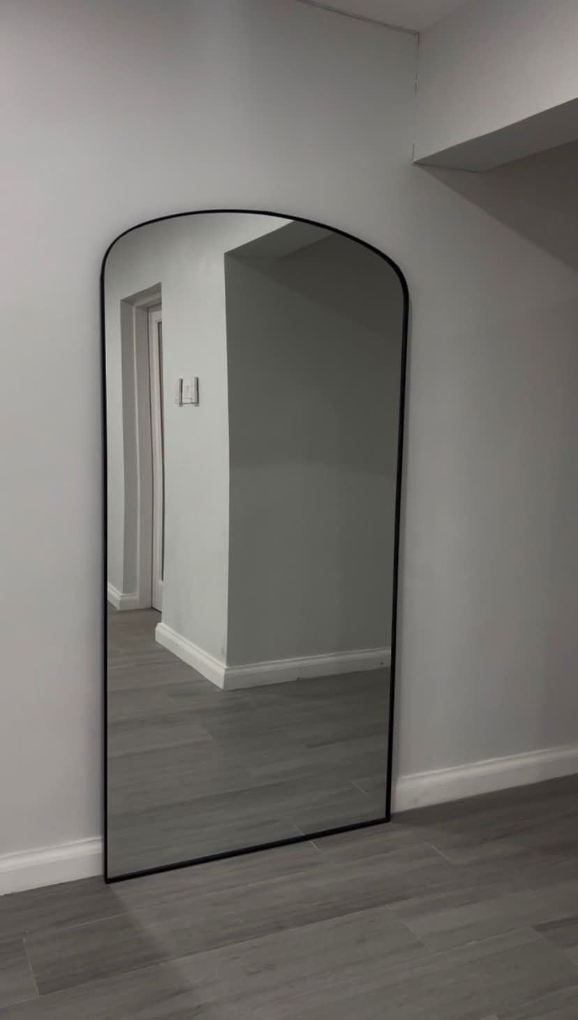 Black arched full-length mirror in a corner